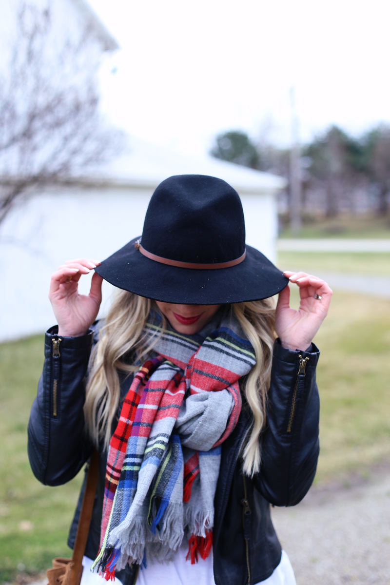 Black hat, black jacket and a plaid scarf.