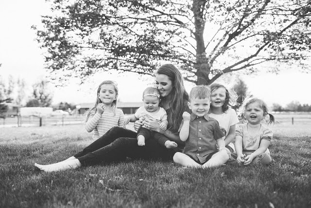 Emily sits on the grass with her five children.